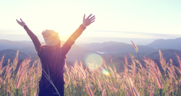 Person with C O P D with hands in the air, happy, in a field.