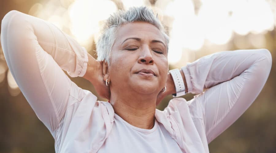 A senior woman with a respiratory disorder breathing and stretching her arms.